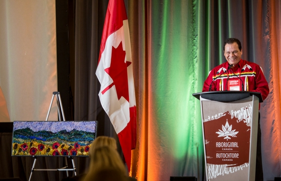 Robert Bernard at the podium on stage next to the Canadian flag at GoMedia 2017